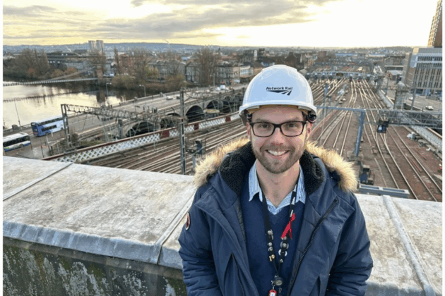 A photo fo Chris Erridge in front of a railway track with a hard hat on